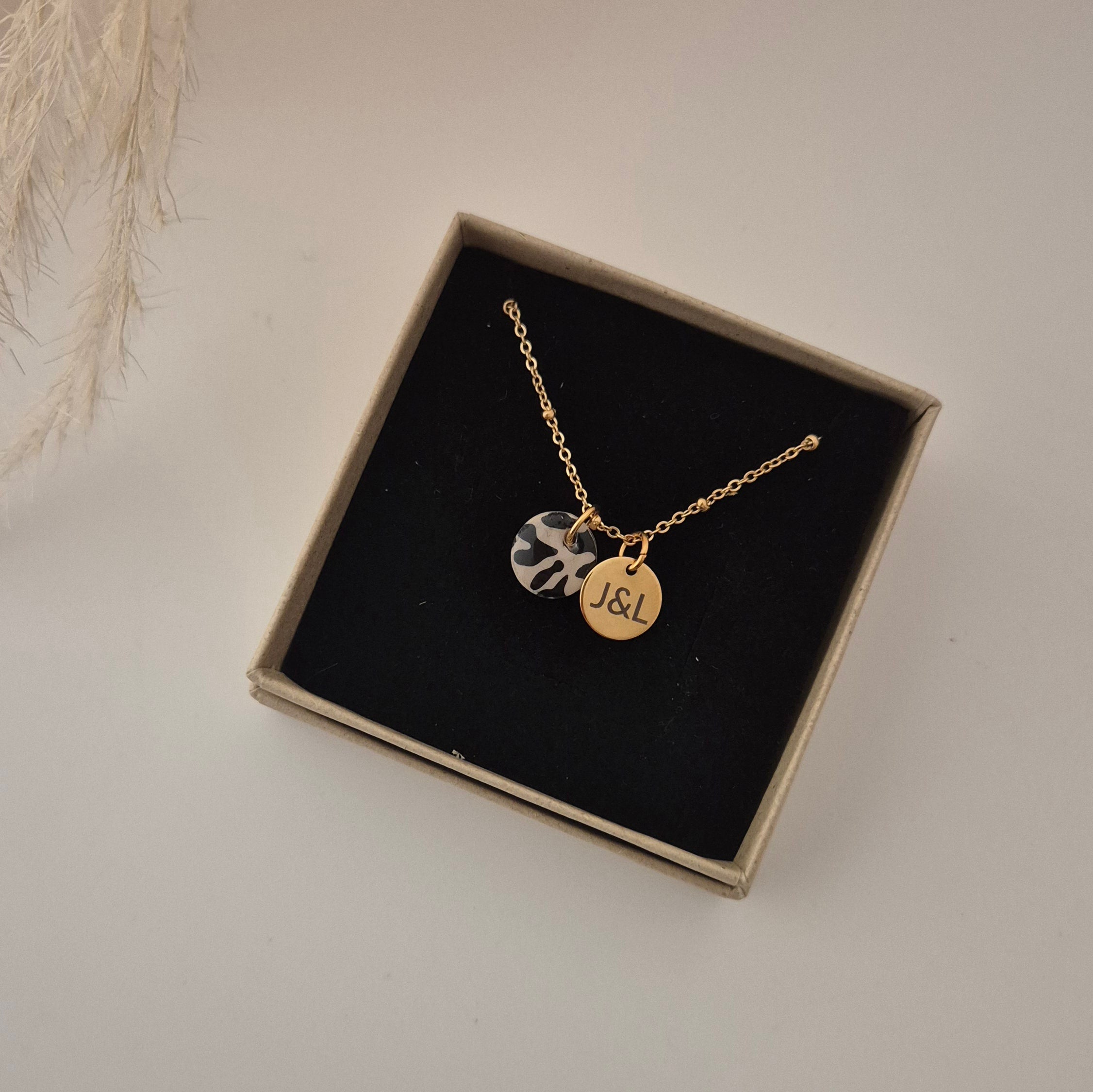 Goldene Kette in der Schmuckschachtel. Leo-Anhänger sowie der goldene Anhänger mit J&L graviert zur Größendarstellung.