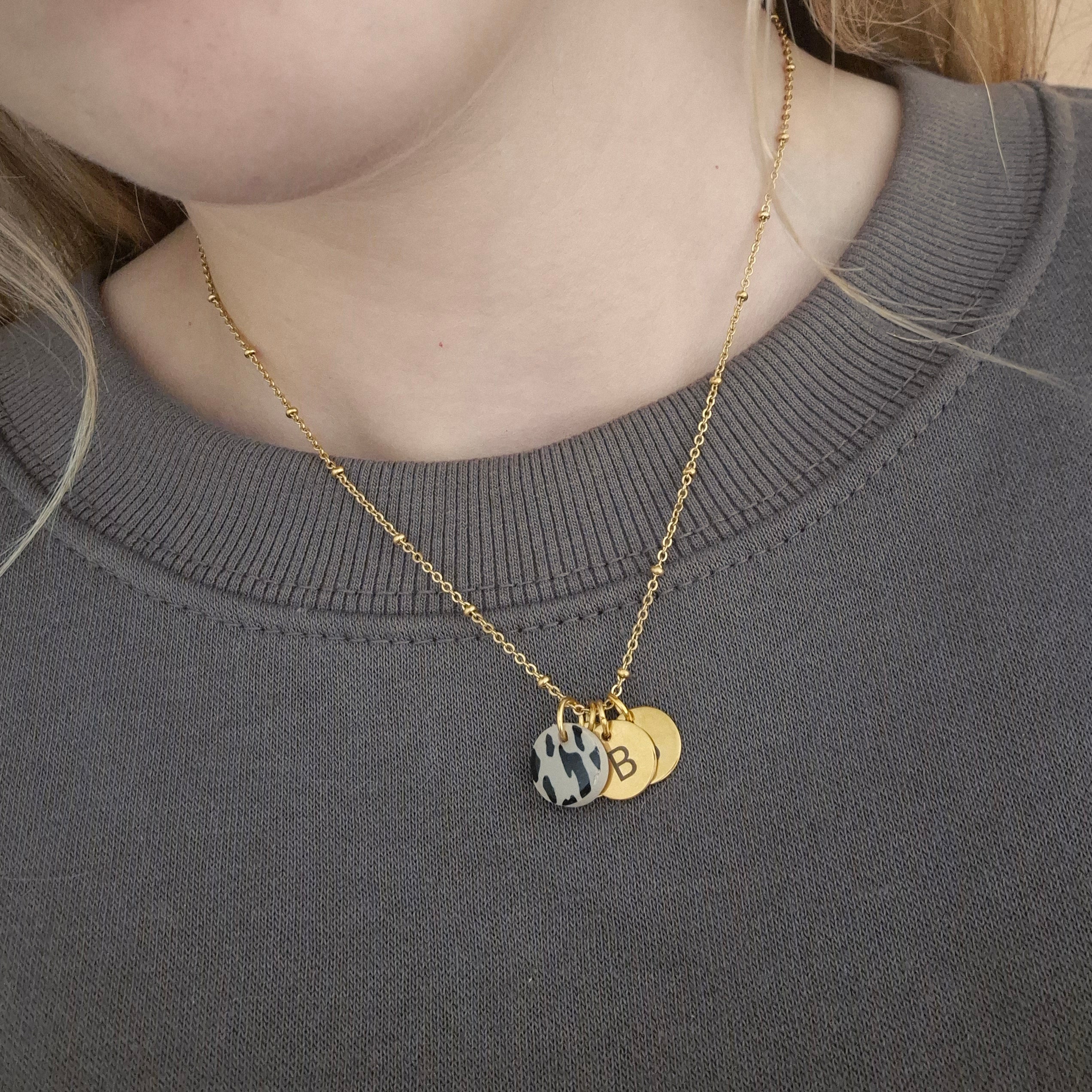 Goldene Kette getragen, auf dem Bild ist zu sehen, wie die Anhänger fallen, sobald man die Kette trägt. Sie liegen leicht hintereinander und der Leo Anhänger hängt vorne.